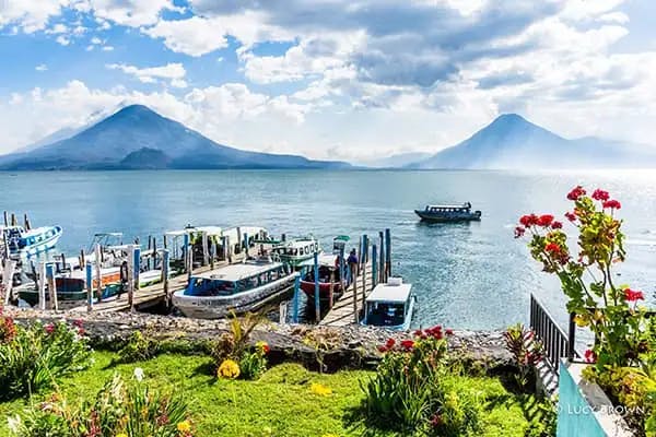 Lanchas moored at Panajachel docks with Atitlán Volcano, Tolimán Volcano, and San Pedro Volcano on the far shore. ©Lucy Brown