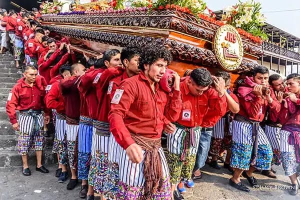 Tz’utujil Maya men wearing traditional garments carry a procession float on Good Friday.
